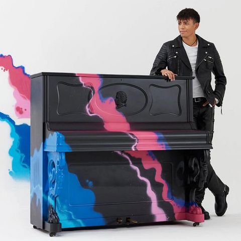 Imagefoto: Pianist Louis Philippson steht an einem Klavier, von links fließt blaue und pinke Farbe ins Bild