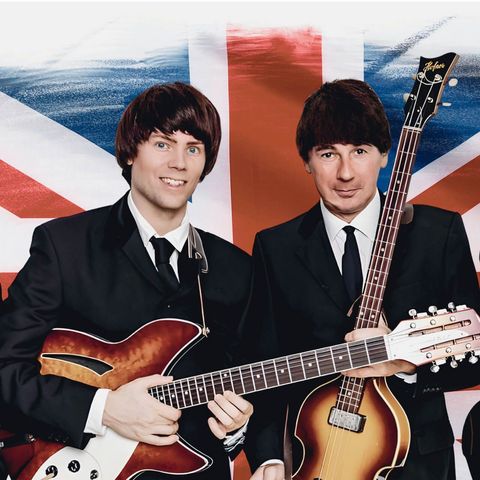 Männer mit Topfschnitt und Instrumenten stehen vor einer britischen Flagge