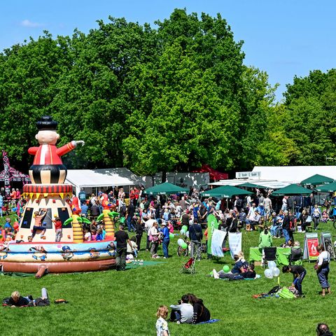 Kinder klettern auf der Hüpfburg und Gäste laufen über die Wiese beim Fahrradfrühling im Mai im MüGa-Park.