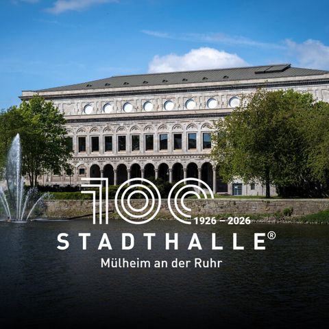 Weißes 100-Jahre-Logo der Stadthalle Mülheim auf einem Foto der Sehenswürdigkeit an der Ruhr, umgeben von grünen Bäumen