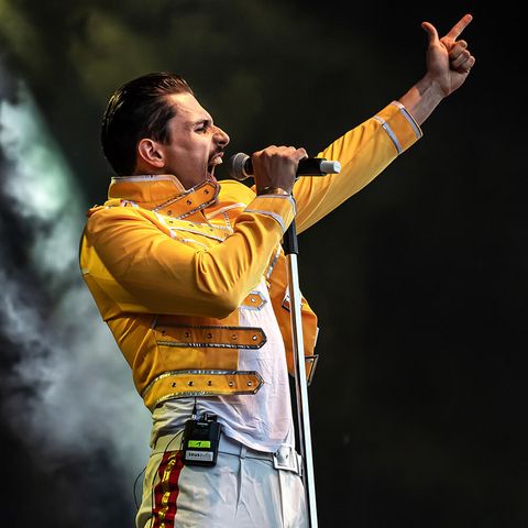 Mann als Queen-Sänger Freddie Mercury gekleidet singt leidenschaftlich in ein Mikrofon