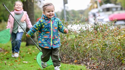 Zwei fröhliche Kinder erkunden mit einem Kescher im Herbst die Ruhr an der Mülheimer Schleuseninsel.