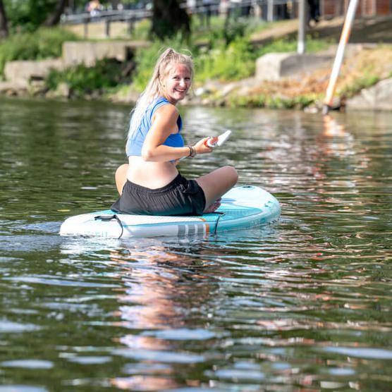 Frau sitzt auf einem SUP im Sommer am Stadthafen Mülheim