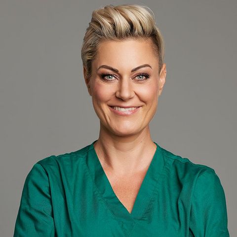 Portrait von Doc Caro in grünem Shirt und mit verschränkten Armen vor grauem Hintergrund