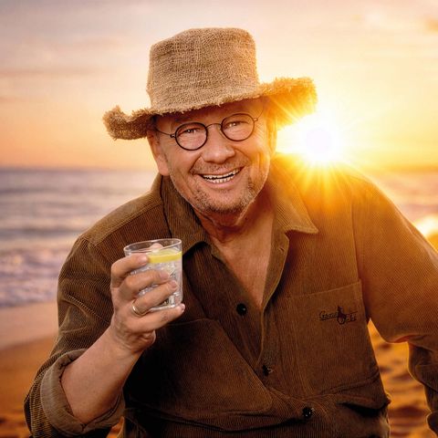 Bernd Stelter mit Strohhut am Strand im Sonnenuntergang.